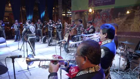 Toma-De-Gran-Angular-De-La-Banda-De-Mariachis-En-El-Escenario-Afuera-Por-La-Noche-Durante-El-Festival-De-Merida-En-Merida,-Mexico