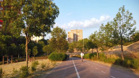 Two-cyclists-and-a-man-riding-an-electric-scooter-driving-on-a-bike-path-in-the-morning