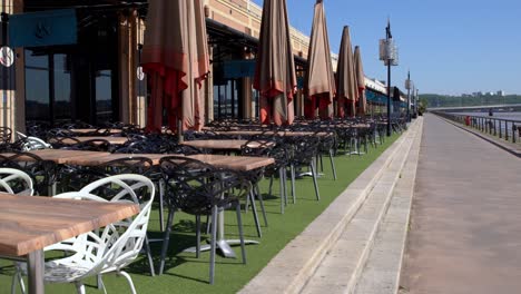 Empty-tables-at-Makila-Kafe-restaurant-on-the-Garonne-river-shore-closed-during-the-COVID-19-pandemic,-Handheld-stable-shot