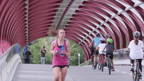 Selective-focus-jogger-jogging-on-Peace-Bridge-with-family-bicycling