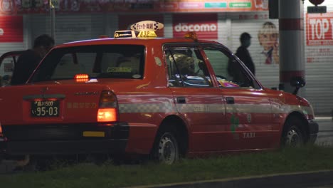 Orangefarbenes-Taxi,-Das-Die-Tür-öffnet,-Damit-Passagiere-Einsteigen-Und-Nachts-In-Der-Bucht-In-Kamata,-Tokio,-Japan-Abfahren-Können