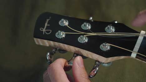 La-Mano-De-Una-Persona-Apretando-Las-Cuerdas-Del-Cabezal-De-La-Máquina-De-Una-Guitarra-Acústica-En-Tokio,-Japón