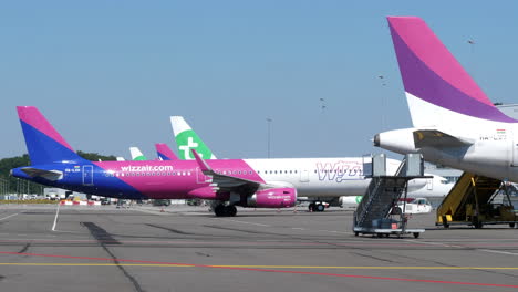 Un-Remolcador-Empujando-Un-Avión-De-La-Aerolínea-Wizzair-En-La-Plataforma-Del-Aeropuerto-De-Eindhoven-En-Eindhoven,-Países-Bajos---Plano-General