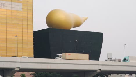 Estructura-Gigante-De-Caca-Dorada-En-La-Cervecería-Asahi-Con-Vehículos-Que-Pasan-Sobre-El-Río-Sumida-En-Asakusa,-Tokio---Plano-Completo