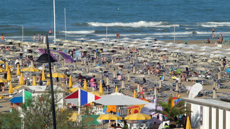 Gente-De-Tiro-Largo-En-Cámara-Lenta-Disfrutando-De-Un-Día-Soleado-En-Una-Playa-Llena-De-Gente