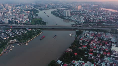 Vuelo-Lento-Aéreo-Sobre-El-Río-Saigón-Hacia-El-Puente-De-Saigón-Con-Barcos-De-Carga-Que-Transportan-Contenedores-De-Envío-Al-Puerto