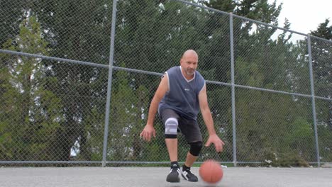 Retrato-De-Un-Hombre-Practicando-Movimientos-De-Baloncesto-Y-Regateando-Frente-A-La-Cámara,-Vista-Amplia