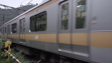 JR-Chuo-train-in-Toky-Japan-passing-through-rural-landscape---view-from-close-to-railway-crossing