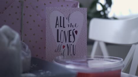 Valentines-Card-With-Pink-Wrapped-Gift-and-Candy,-Handheld-Close-Up-Shallow-Depth-of-Field