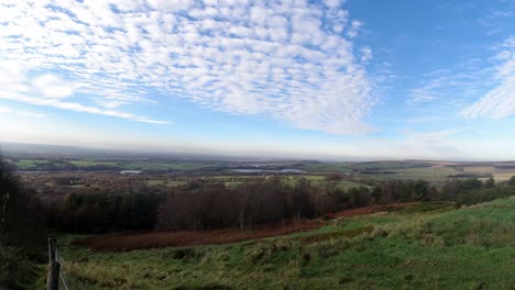 People-hiking-in-autumn-woodland-countryside-timelapse-clouds-casting-shadows-across-rural-landscape