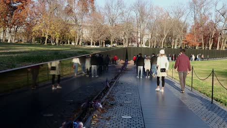 Visitors-to-the-Vietnam-War-Memorial-wall-in-Washington,-DC-walk-past-names-of-American-soldiers-missing-or-killed-during-the-Vietnam-War