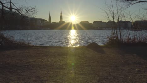 Vista-De-La-Puesta-De-Sol-En-Hamburgo,-Alemania,-En-Diciembre-De-2019-A-Través-Del-Lago-Alster-Interior-Con-Gente-Caminando