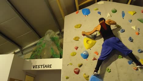 A-young-man-practicing-on-a-climbing-wall-inside-a-building