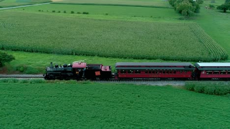 Tren-De-Vapor-Resoplando-A-Lo-Largo-De-Las-Tierras-De-Cultivo-Amish-Visto-Por-Un-Dron