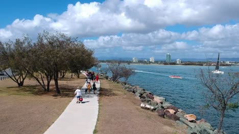 Far-view-of-a-group-of-children-and-adults-walking-along-a-path-near-the-ocean-to-go-snorkelling