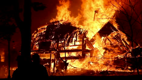 Die-Silhouette-Einiger-Feuerwehrmänner,-Die-Einen-Haufen-Schutt-Beobachten,-Der-In-Einem-Riesigen-Feuer-Brennt