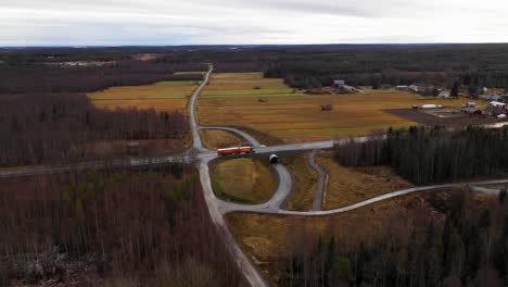 Vista-Aérea-De-La-Conducción-De-Camiones-Semi-En-La-Carretera-Entre-El-Bosque-Y-Los-Campos