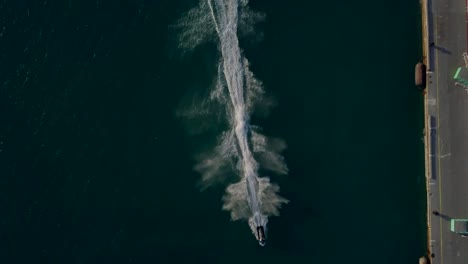 Aerial-view-of-two-jet-skies-sailing-in-front-of-a-cruise-ship-and-the-camera-panning-down-to-get-a-overview-of-the-jet-skies-sailing-by-4K