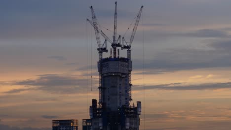 Un-Video-De-Lapso-De-Tiempo-De-La-Grúa-Y-El-Sitio-De-Construcción-Contra-El-Cielo-Azul-Con-Una-Vista-Fascinante-Del-Anochecer