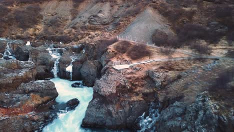 Drone-with-cinematic-movements-shows-beautiful-icelandic-waterfall,-Hraunfossar,-in-sunset-light-from-multiple-angles