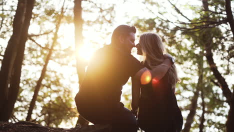 Young-couple-in-love-sitting-on-the-grass-in-the-forest-during-sunset