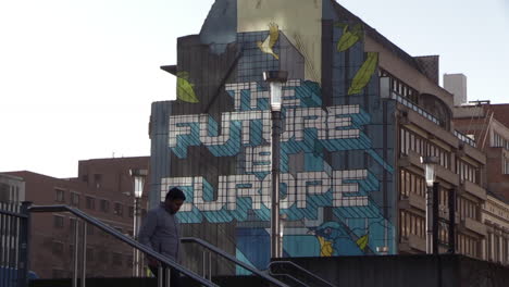 a-foreign-man-walks-in-front-of-a-building-with-graffiti