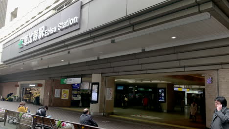 People-waiting-on-bench-and-talk-by-phone-at-West-entrance-exit-of-Ebisu-Station