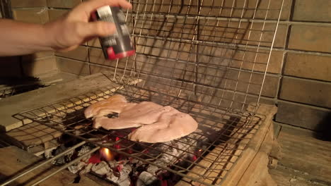 Toma-En-Cámara-Lenta-Del-Hombre-Agregando-Condimentos-Al-Pollo-A-La-Parrilla-En-Una-Barbacoa-De-Carbón-Por-La-Noche