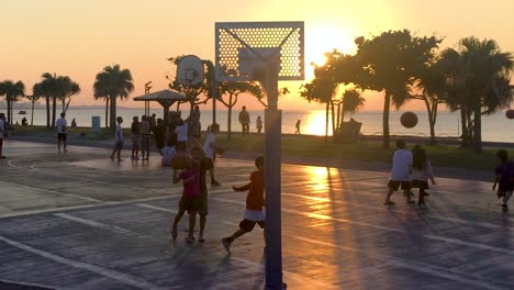 Los-Adolescentes-Juegan-Juegos-De-Baloncesto-En-Las-Canchas-Al-Lado-Del-Océano-Durante-La-Noche-Al-Atardecer