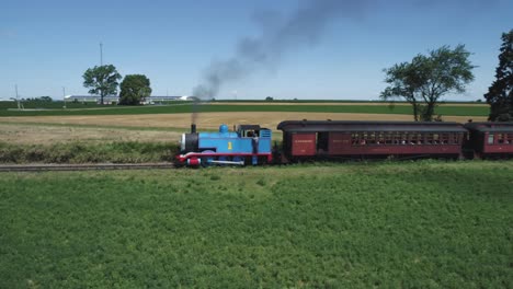 Luftaufnahme-Eines-Thomas-The-Tank-Engine-Mit-Passagierwagen,-Die-Entlang-Der-Amischen-Landschaft-Schnaufen