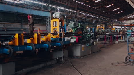 A-panning-view-of-a-steel-rods-factory,-A-man-is-standing-on-the-machines,-perspective-view