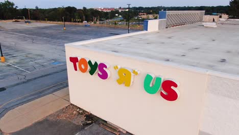 Descending-aerial-of-empty-Toys-R-Us-parking-lot,-bankruptcy,-Amazon-effect,-e-commerce-impact