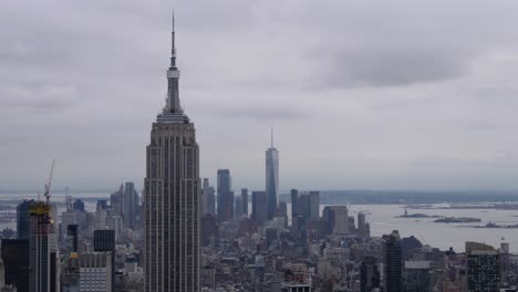 Lapso-De-Tiempo-De-Las-Nubes-Sobre-El-Empire-State-Building-Y-El-One-World-Trade-Center,-Y-El-Tráfico-De-Barcos-En-El-Río-Hudson-En-El-Fondo-Que-Conduce-A-La-Isla-De-La-Libertad-En-La-Ciudad-De-Nueva-York,-Junio-De-2019