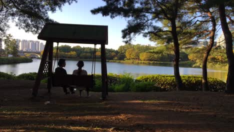 A-mother-and-a-daughter-chat-on-a-swing-at-Janghang-dong,-Ilsan-gu,-Goyang-si,-Gyeonggi-do,-South-Korea