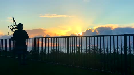 Gaitero-Frente-A-Una-Magnífica-Puesta-De-Sol-En-La-Cima-De-Un-Acantilado-Costero-Con-Vistas-A-La-Bahía-De-La-Media-Luna