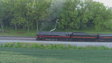 Una-Vista-Aérea-De-Un-Tren-De-Vapor-No-611-Que-Sopla-Humo-A-Través-Del-Campo-Agrícola-En-Un-Día-Soleado-De-Verano-Con-Campos-Verdes