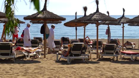 4k-Pareja-De-Ancianos-En-Busca-De-Tumbonas-En-La-Playa-De-Marbella,-Málaga,-España,-Vacaciones-En-La-Costa-Del-Sol