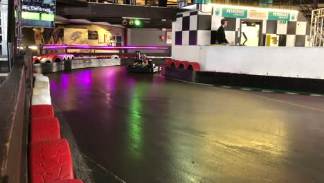 Rear-view-of-kids-driving-by-in-carts-on-an-indoor-race-circuit