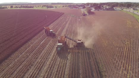 Vista-Giratoria-Aérea-Desde-La-Parte-Delantera-De-Una-Cosechadora-Recogiendo-Maíz-Para-La-Cosecha-Del-Próximo-Año-Mientras-Otro-Tractor-Gira-En-El-Fondo