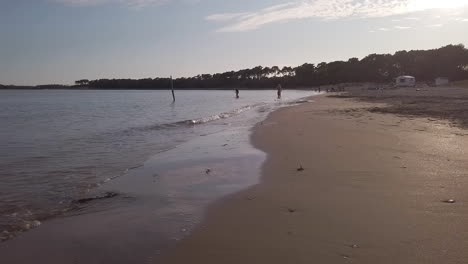 Dos-Mujeres-De-Vacaciones-Nadando-Al-Atardecer-En-La-Playa-De-Gatseau,-Isla-De-Oleron