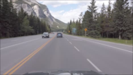 Landschaftsansicht-Der-örtlichen-Straße,-Die-Aus-Dem-Fahrenden-Auto-Nach-Banff-City-Führt,-Während-Man-An-Sommertagen-Durch-Den-Kiefernwald-Mit-Klarem-Blauen-Himmel-Rennt