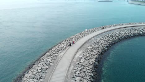 Circular-aerial-shot-from-drone-of-people-standing-on-stone-bridge-in-the-water,-Abu-Dhabi,-UAE