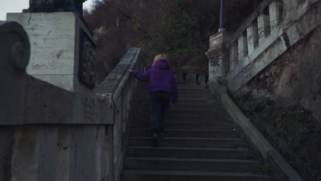 Back-View-Of-A-Pretty-Woman-Walking-Up-On-An-Old-Stairway-In-Budapest-Hungary-On-A-Cloudy-Weather---Medium-Shot