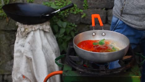 A-slow-motion-shot-of-a-street-vendor-adding-oil,-Chilly-sauce,-and-some-ingredients-into-the-sauce-pan-to-make-Chilly-Chicken-and-sell-it-in-the-streets-of-Darjeeling