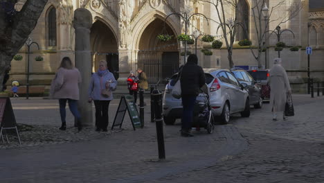 People-Passing-by-Restored-Ancient-High-Cross-Monument-in-Cornwall's-Truro-City-Centre-with-Golden-Sun-Light-on-Cathedral-in-Background---Wide-Shot