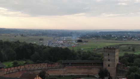 Aerial-View-of-Music-Festival-in-a-Field-in-the-Distance-Flying-Over-Castle-in-Europe