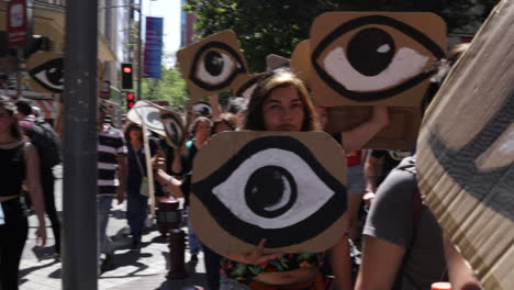 Protesters-walk-the-streets-of-Santiago,-holding-signs-with-eyes-painted-on-them