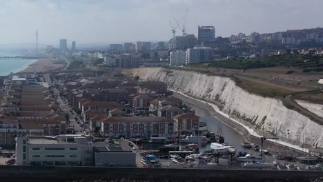 Rising-establishing-shot-of-Brighton-Marina,-apartments---the-strand-with-the-town,-Pier,---i360-in-the-background