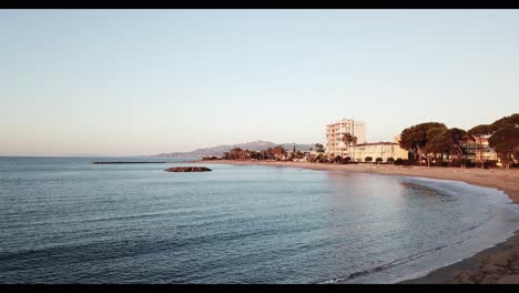 Aerial-view-dolly-in-shot-of-sandy-beach-early-morning-sunrise-Cambrils,-Costa-Dorada,-Spain