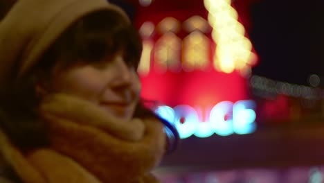 Nov-2019,-Paris,-France:-a-woman-posing-in-from-of-the-famous-Moulin-Rouge-beautifully-illuminated-at-night